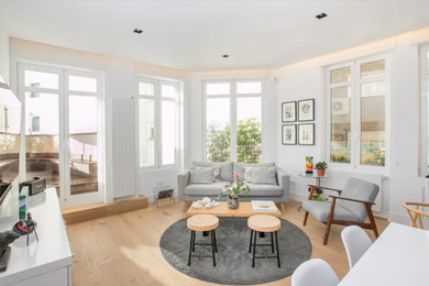 Diseño de sala de estar abierta actual de tamaño medio sin chimenea con paredes blancas, televisor colgado en la pared, suelo marrón y suelo de madera clara