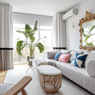Modelo de sala de estar escandinava, de tamaño medio, sin chimenea, con televisor colgado en la pared, paredes grises y suelo de madera clara