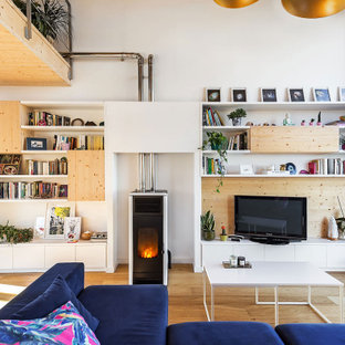 Modelo de sala de estar con biblioteca abierta, contemporánea, grande, con paredes blancas, suelo de madera clara, estufa de leña, marco de chimenea de metal, televisor independiente y suelo beige