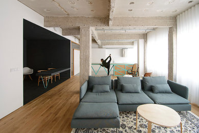 Imagen de sala de estar abierta industrial grande sin chimenea con paredes blancas y suelo de madera en tonos medios