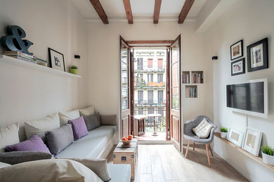 Modelo de sala de estar abierta escandinava pequeña sin chimenea con paredes blancas, suelo de madera clara, televisor colgado en la pared y suelo beige