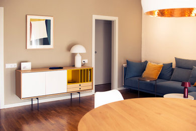 Ejemplo de sala de estar abierta minimalista con paredes beige, suelo de madera en tonos medios y pared multimedia