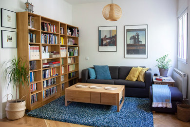 Modelo de sala de estar con biblioteca contemporánea con paredes blancas, suelo de madera en tonos medios y suelo marrón