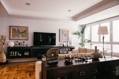 Imagen de sala de estar abierta ecléctica de tamaño medio sin chimenea con paredes blancas, suelo de madera en tonos medios y pared multimedia