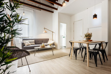 Imagen de sala de estar abierta nórdica de tamaño medio con paredes blancas, suelo de madera clara y suelo beige