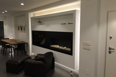 Ejemplo de sala de estar abierta minimalista de tamaño medio con paredes blancas, suelo de baldosas de porcelana, chimenea lineal, marco de chimenea de metal y pared multimedia