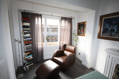 Ejemplo de sala de estar con biblioteca cerrada tradicional renovada de tamaño medio sin chimenea y televisor con paredes blancas y suelo de madera en tonos medios