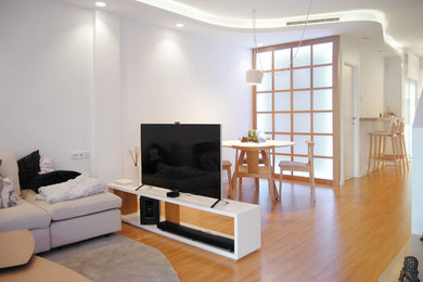 Imagen de sala de estar con biblioteca abierta minimalista pequeña sin chimenea con paredes blancas, suelo de madera en tonos medios, televisor independiente y suelo marrón