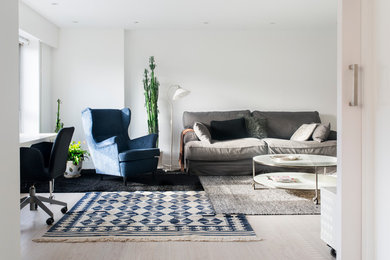 Imagen de sala de estar abierta escandinava de tamaño medio sin chimenea con paredes blancas y suelo de madera clara