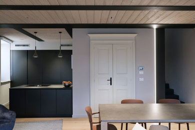 Cette image montre une salle à manger ouverte sur la cuisine minimaliste de taille moyenne avec un mur gris, parquet clair, aucune cheminée et un sol beige.