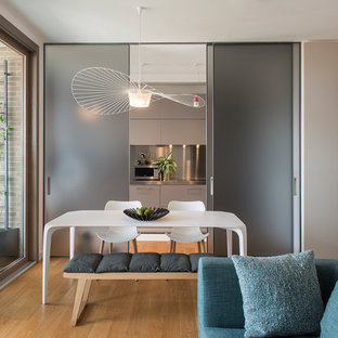 Foto di una sala da pranzo aperta verso la cucina minimal con pareti bianche e parquet chiaro