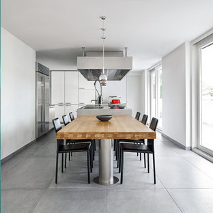 Foto di una sala da pranzo aperta verso la cucina contemporanea con pareti bianche e pavimento grigio