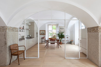 Idee per una sala da pranzo aperta verso la cucina mediterranea con pareti bianche e parquet chiaro