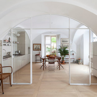 Idee per una sala da pranzo aperta verso la cucina mediterranea con pareti bianche e parquet chiaro