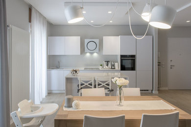 Idée de décoration pour une salle à manger ouverte sur la cuisine design de taille moyenne avec un mur blanc et parquet clair.