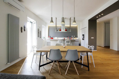 Esempio di una grande sala da pranzo aperta verso il soggiorno contemporanea con pareti bianche, pavimento in legno verniciato e pavimento marrone