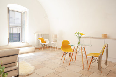Foto di una sala da pranzo aperta verso il soggiorno scandinava con pareti bianche, pavimento in terracotta, camino classico, pavimento beige e soffitto a volta