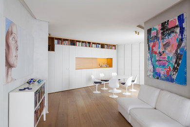 Esempio di una sala da pranzo aperta verso il soggiorno design di medie dimensioni con pareti bianche, pavimento in legno massello medio e pavimento marrone