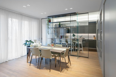 Foto di una sala da pranzo aperta verso il soggiorno minimalista di medie dimensioni con pareti grigie e pavimento in legno massello medio