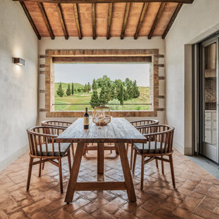Ispirazione per una sala da pranzo mediterranea di medie dimensioni con pareti beige, pavimento in terracotta, pavimento marrone e soffitto in legno