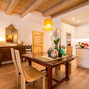 Foto di una sala da pranzo aperta verso la cucina bohémian con pareti bianche, parquet chiaro e pavimento marrone