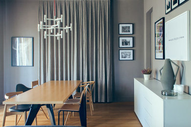 Ejemplo de comedor retro de tamaño medio abierto con paredes grises y suelo de madera clara
