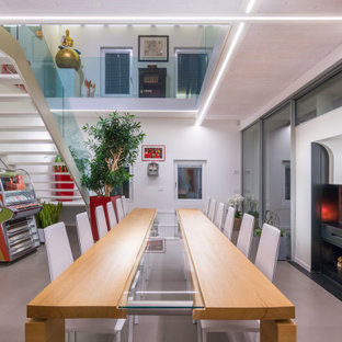 Esempio di una sala da pranzo contemporanea con pareti bianche, camino classico e pavimento grigio
