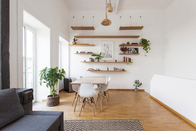 Foto di una grande sala da pranzo aperta verso il soggiorno scandinava con pareti bianche, pavimento in legno massello medio, nessun camino e pavimento beige