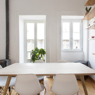 Foto di una sala da pranzo aperta verso il soggiorno scandinava con pareti bianche, pavimento in legno massello medio, stufa a legna e pavimento marrone