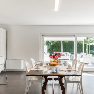 Immagine di una sala da pranzo aperta verso il soggiorno bohémian di medie dimensioni con pareti bianche, nessun camino e pavimento nero