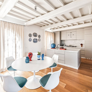Immagine di una sala da pranzo aperta verso la cucina mediterranea con pavimento in legno massello medio e pareti bianche
