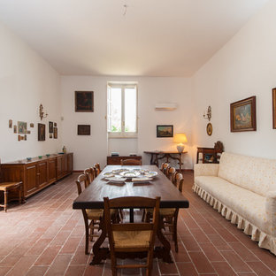 Immagine di una sala da pranzo aperta verso il soggiorno mediterranea con pareti bianche, pavimento in terracotta e pavimento rosso