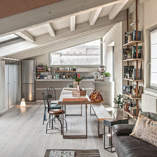 Esempio di una sala da pranzo aperta verso il soggiorno industriale con pareti beige, parquet chiaro e pavimento grigio