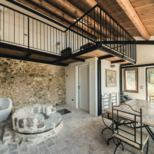 Foto di una grande sala da pranzo mediterranea con pareti bianche, pavimento in mattoni e pavimento grigio