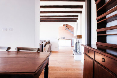 Diseño de comedor actual pequeño con paredes blancas, suelo de madera clara, todas las chimeneas y suelo marrón
