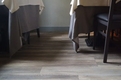 Immagine di una piccola sala da pranzo aperta verso il soggiorno minimalista con pareti bianche, pavimento in vinile e pavimento marrone