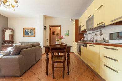Immagine di una piccola sala da pranzo aperta verso il soggiorno chic con pareti bianche, pavimento in terracotta, stufa a legna, cornice del camino in metallo e pavimento arancione