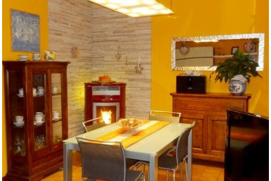 ミラノにある低価格の中くらいなトラディショナルスタイルのおしゃれなLDK (オレンジの壁、セラミックタイルの床、薪ストーブ、茶色い床) の写真