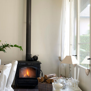 Offenes, Kleines Shabby-Style Esszimmer mit beiger Wandfarbe, Kalkstein, Kaminofen, Kaminumrandung aus Metall und grauem Boden in Mailand