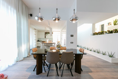 Foto di una grande sala da pranzo aperta verso il soggiorno contemporanea con pareti bianche, parquet scuro, camino bifacciale e pavimento grigio