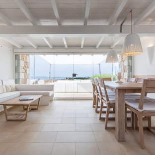 Foto di una sala da pranzo aperta verso il soggiorno costiera con pareti bianche e pavimento beige