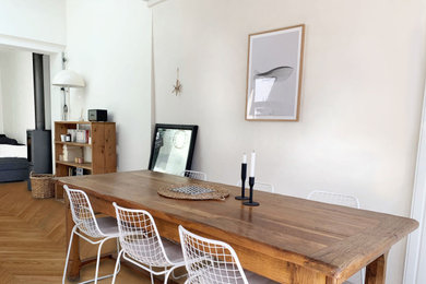 Cette photo montre une grande salle à manger ouverte sur le salon rétro avec un mur blanc, parquet clair, un poêle à bois, un manteau de cheminée en métal et un plafond en bois.