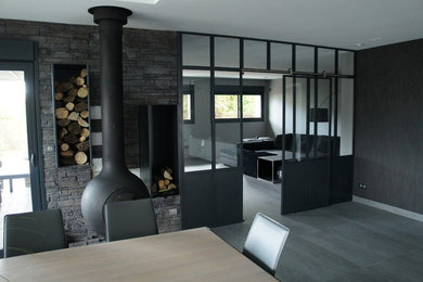 Inspiration pour une salle à manger design fermée et de taille moyenne avec un mur gris, un manteau de cheminée en métal et un sol gris.