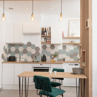 Cette photo montre une salle à manger ouverte sur la cuisine tendance avec un mur blanc et un sol multicolore.