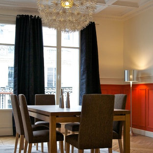 Cette image montre une salle à manger design fermée et de taille moyenne avec un mur rouge et un sol en bois brun.