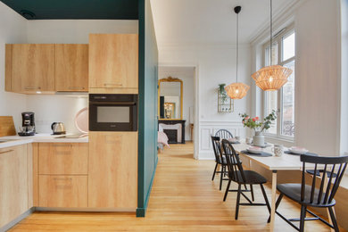 Inspiration pour une salle à manger ouverte sur la cuisine nordique avec un mur vert, parquet clair, une cheminée standard et un manteau de cheminée en pierre.