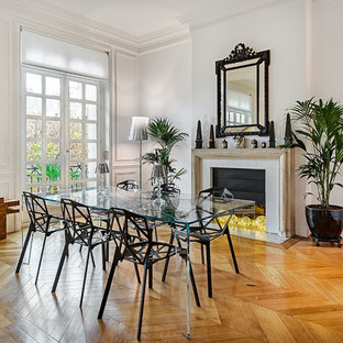 Inspiration pour une salle à manger ouverte sur le salon traditionnelle avec un mur blanc, une cheminée standard, un manteau de cheminée en pierre et un sol en bois brun.