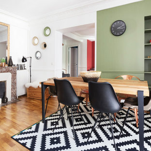 Inspiration pour une salle à manger design fermée et de taille moyenne avec un mur vert, un sol en bois clair et une cheminée standard.