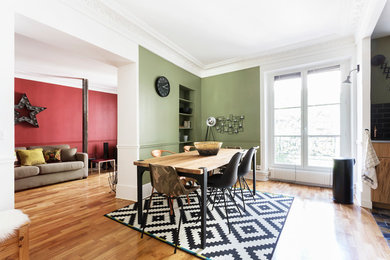Aménagement d'une salle à manger ouverte sur le salon contemporaine de taille moyenne avec parquet clair, une cheminée standard, un manteau de cheminée en pierre et un mur vert.