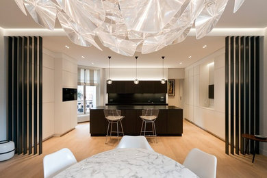 This is an example of a large contemporary open plan dining room in Paris with white walls, light hardwood flooring and no fireplace.